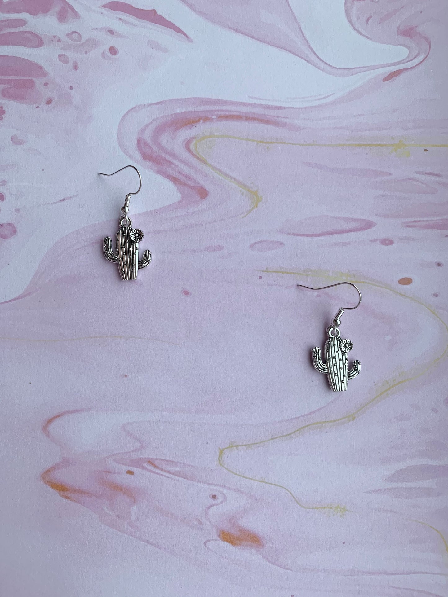 Dangly novelty earrings. Silver coloured alloy cacti charms with spikes and flower on silver plated hooks. Cheap cute earrings.