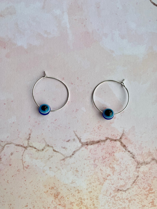 Small evil eye spherical bead on silver plated hoop earrings. Colours from outside to inside of the evil eye are dark blue, white, light blue, black. Hoop earrings. Spiritual earrings. Earrings for women.