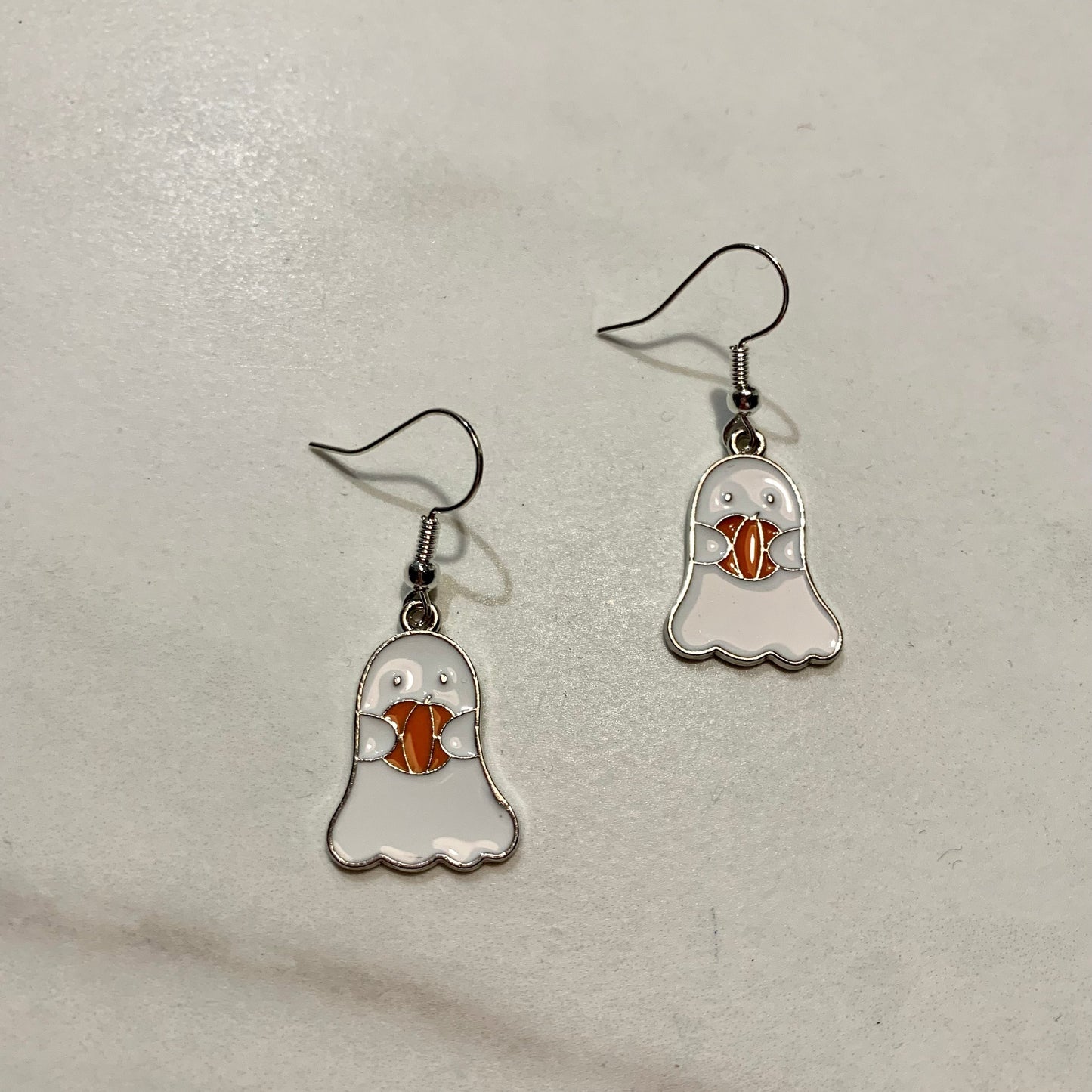 Earrings with a white ghost holding an orange pumpkin