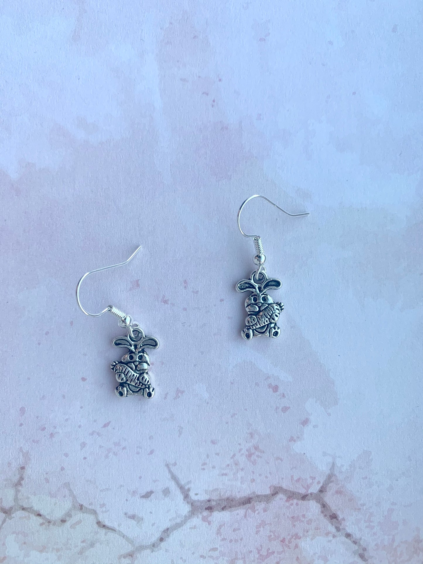Alloy silver cartoon bunny holding oversized bunny charm on silver plated hooks earrings. easter earrings. Novelty easter earrings. Novelty earrings. Animal earrings.