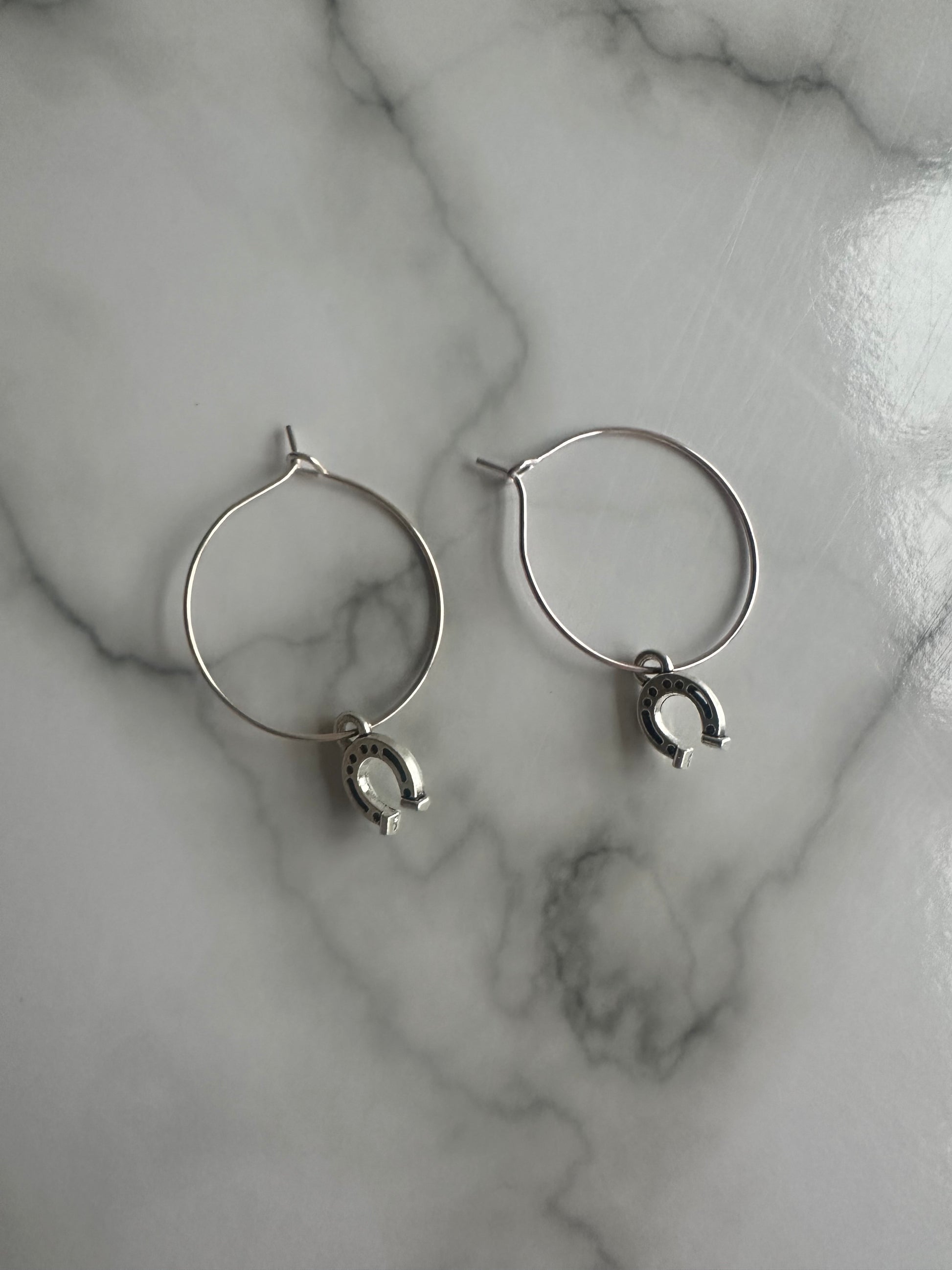 Elegant silver horseshoe earrings on hoops, lightweight and perfect for equestrian enthusiasts or western-style outfits.
