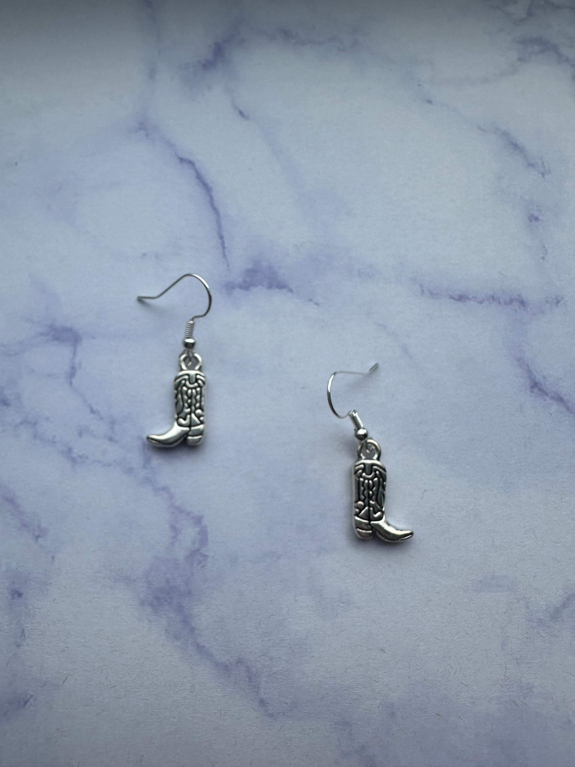 Country western earrings shaped like cowboy boots with silver details on silver plated hooks. 