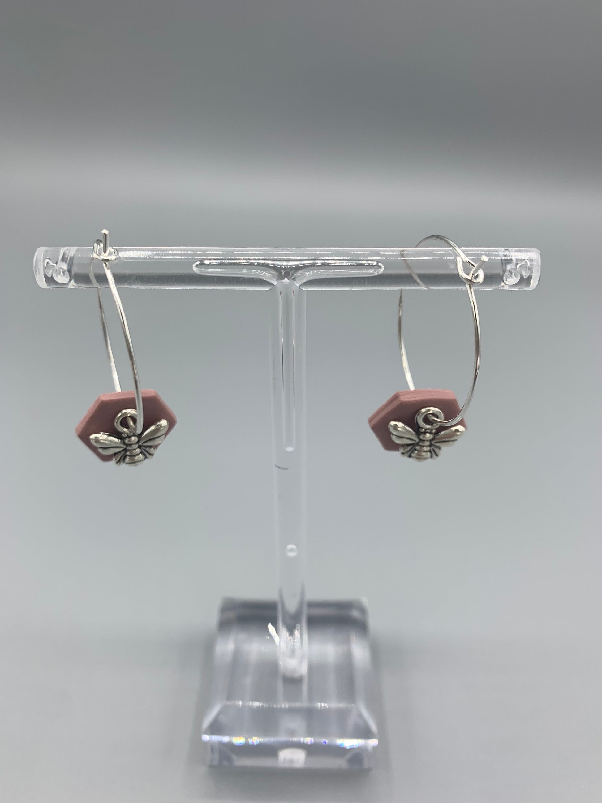 Alloy silver small bee charms on silver plated hoop earrings with an antique pink coloured fimo clay hexagonal disc behind the bee charm. 