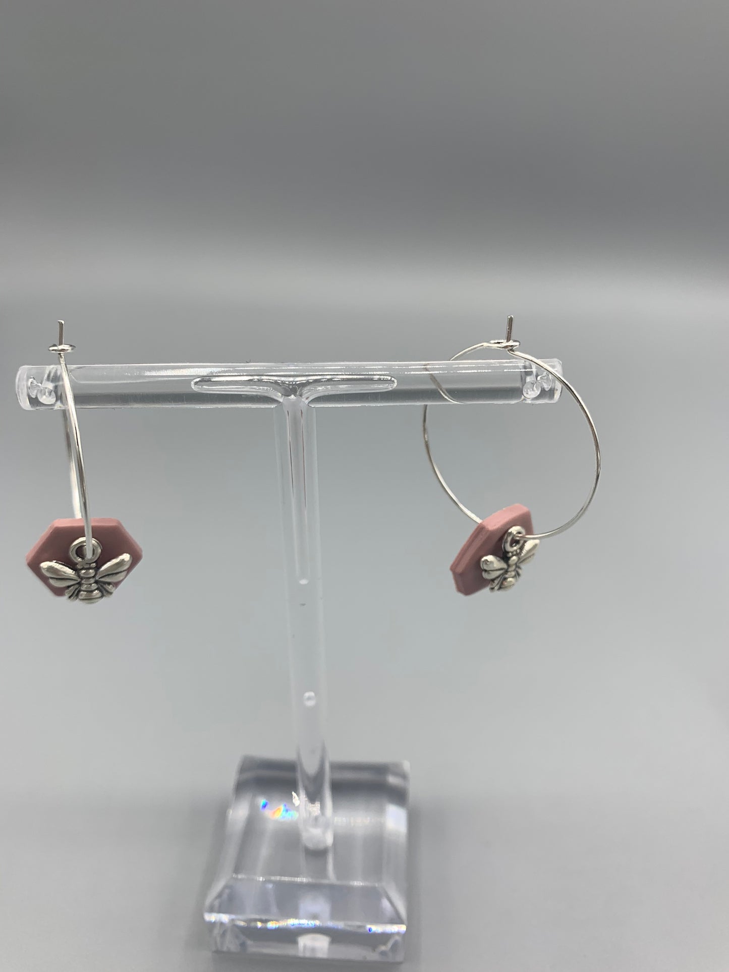 Alloy silver small bee charms on silver plated hoop earrings with an antique pink coloured fimo clay hexagonal disc behind the bee charm. 
