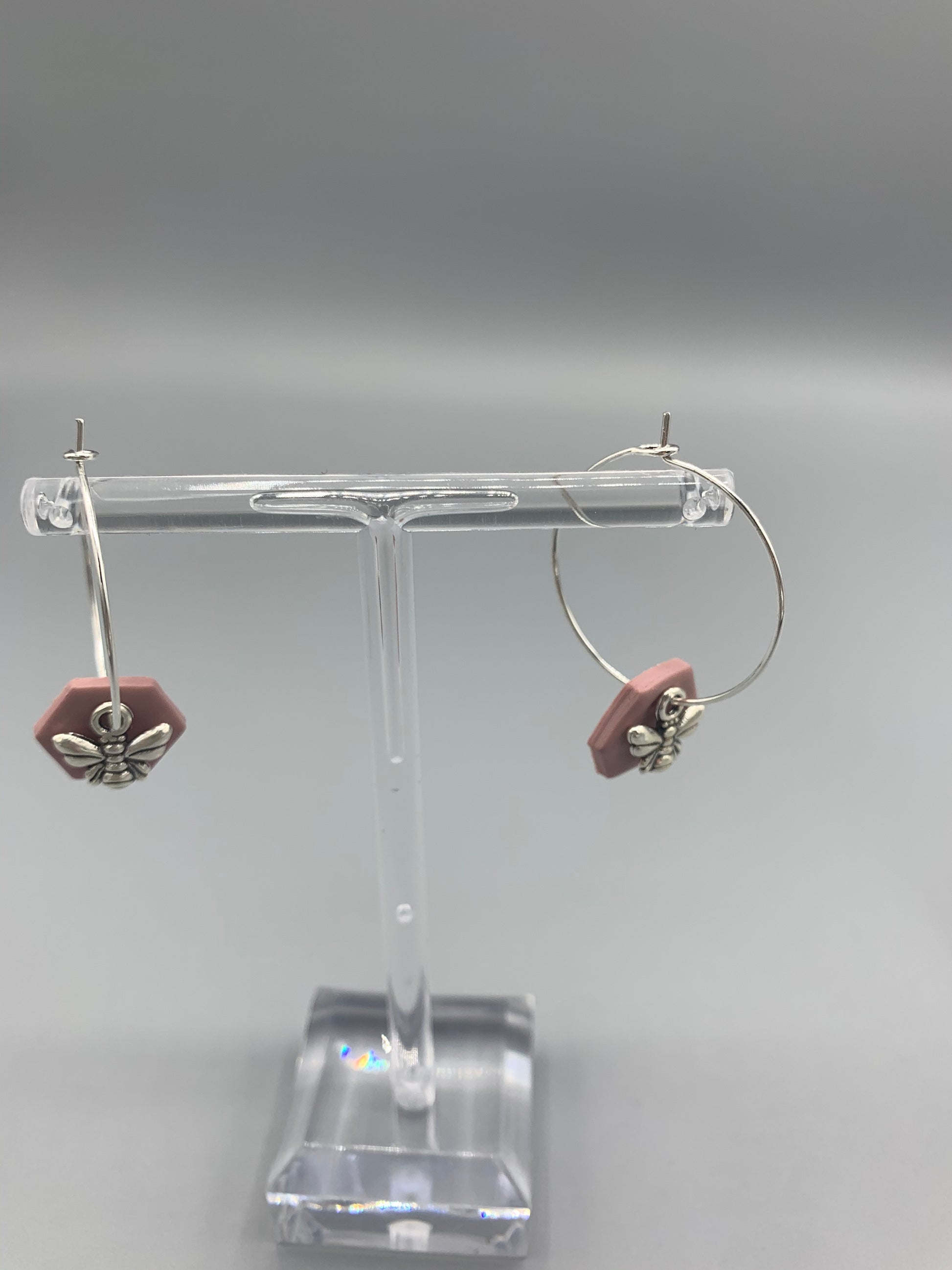 Alloy silver small bee charms on silver plated hoop earrings with an antique pink coloured fimo clay hexagonal disc behind the bee charm. 