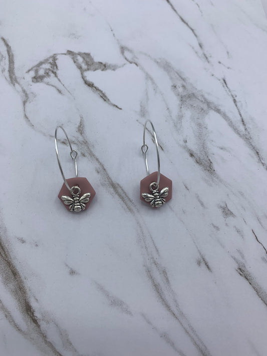Alloy silver small bee charms on silver plated hoop earrings with an antique pink coloured fimo clay hexagonal disc behind the bee charm. 