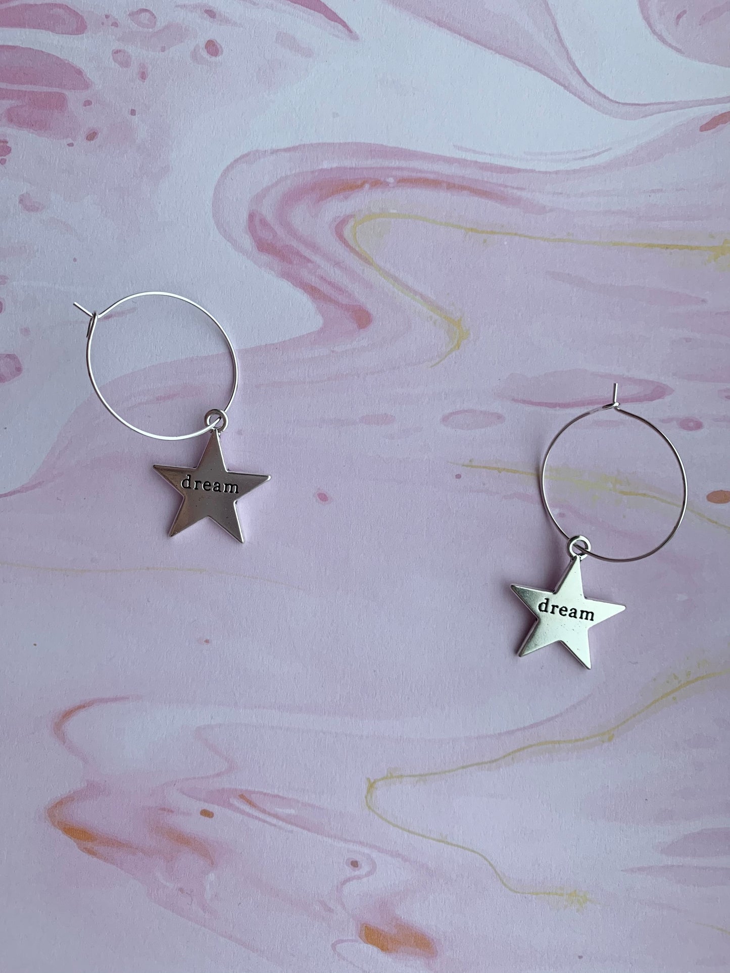 Large star silver coloured alloy charm with the word dream embossed across the centre on silver plated hoops. Hamilton earrings. Dream earrings. 