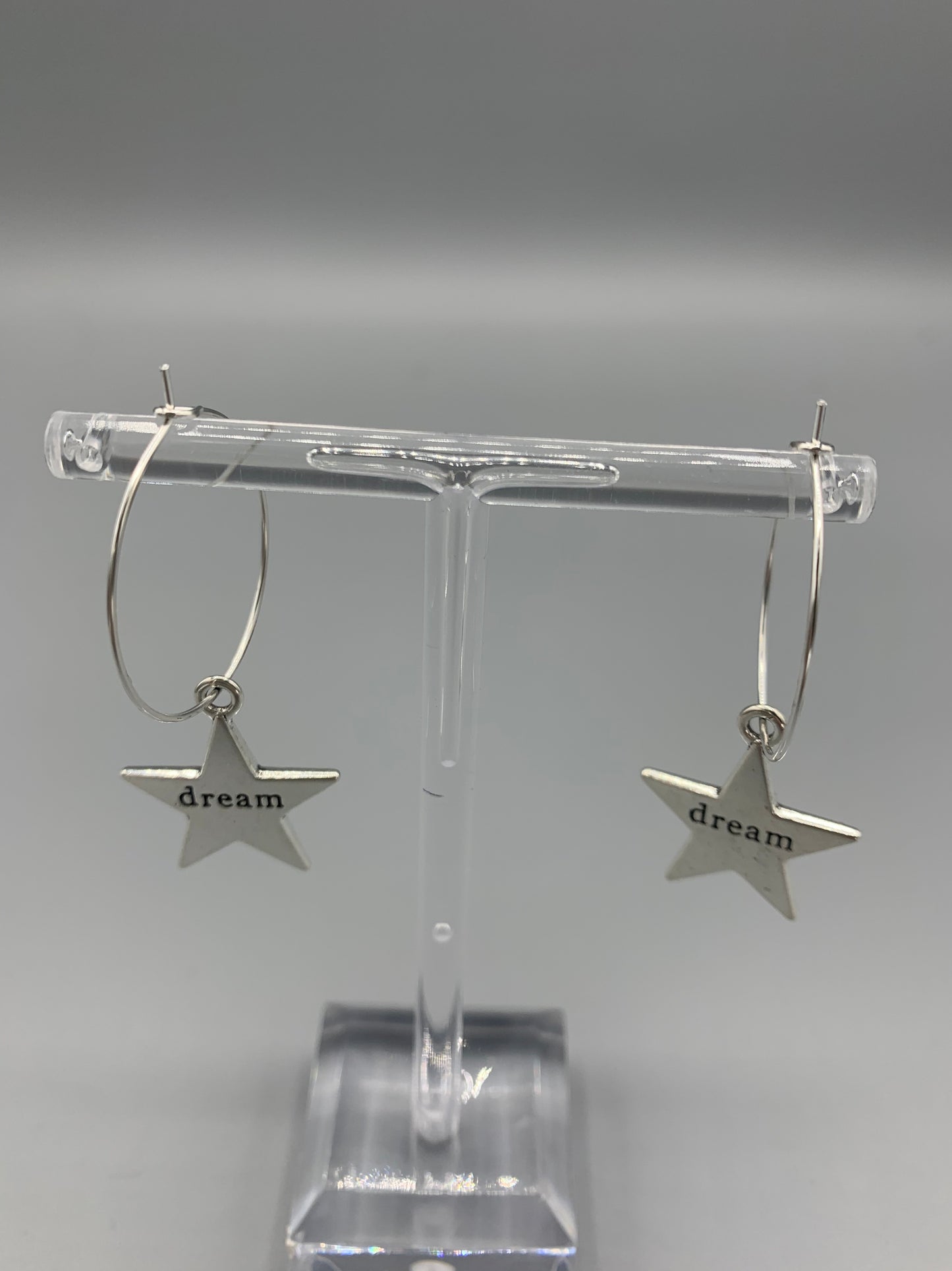 Large star silver coloured alloy charm with the word dream embossed across the centre on silver plated hoops. Hamilton earrings. Dream earrings. buy earrings. 