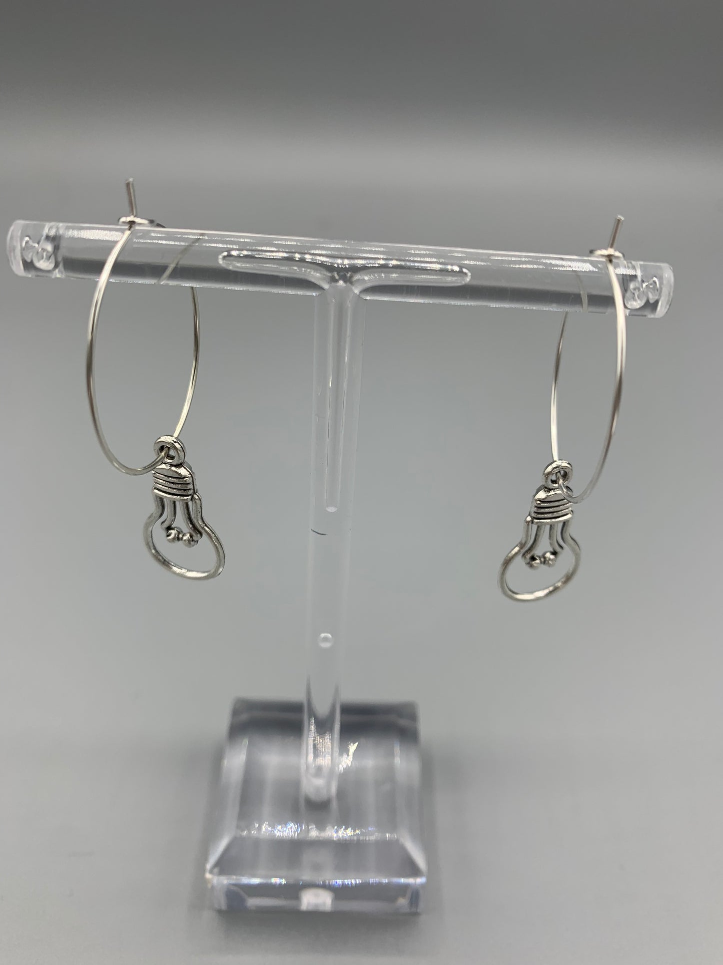 An alloy silver coloured charm that is the outline of a round light bulb on silver plated hoops. Novelty earrings and perfect for thinking of ideas. Great gift for people that are creative or writing a book. 