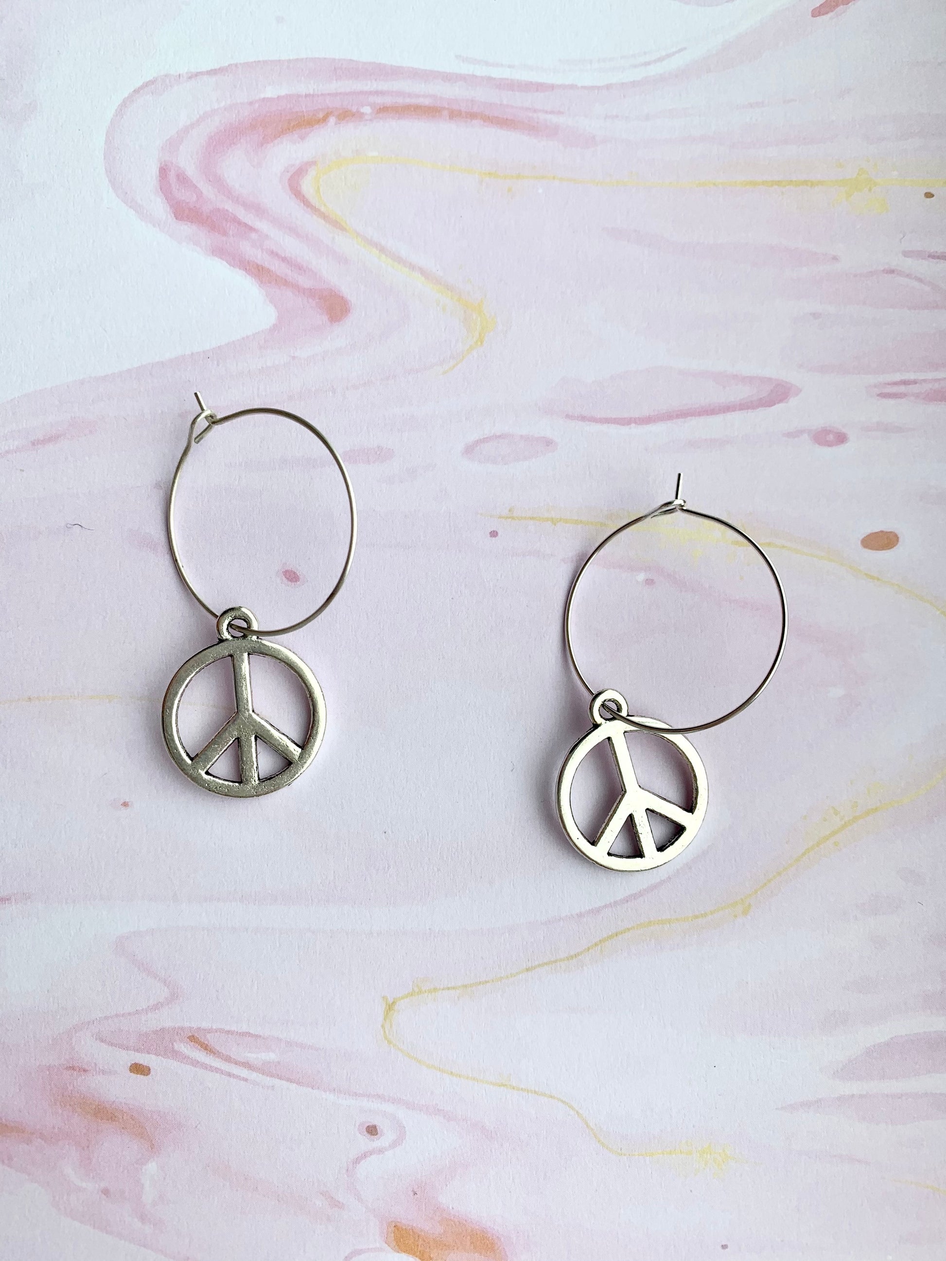 peace earrings. peace symbol silver coloured charm on silver plated hoops. hoop earrings. peace not war. statement earrings. 