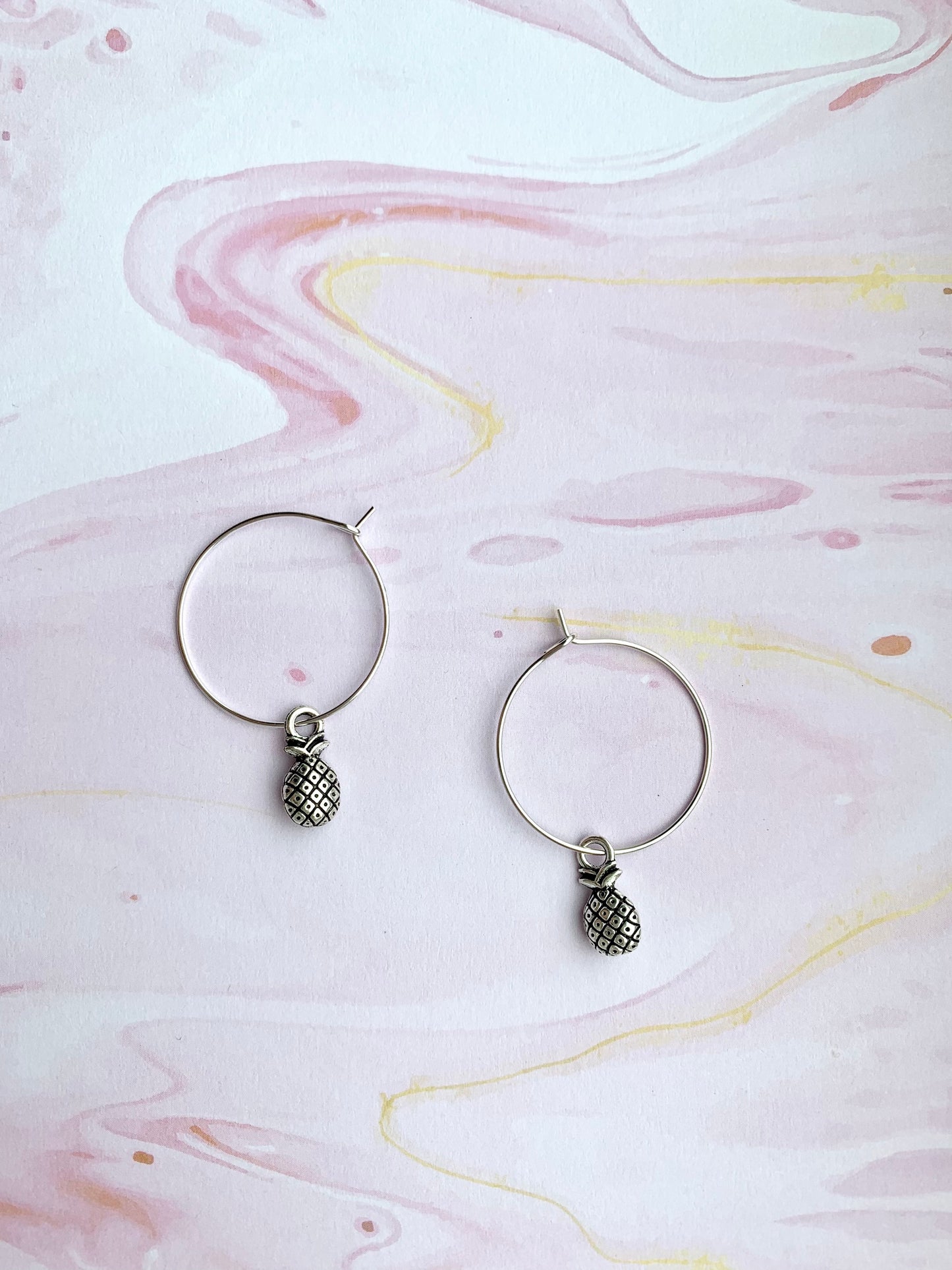 Super cute pineapple earrings. Small silver coloured pineapple charm on silver plated hoos. hoop earrings. popular earrings. cheap earrings. 