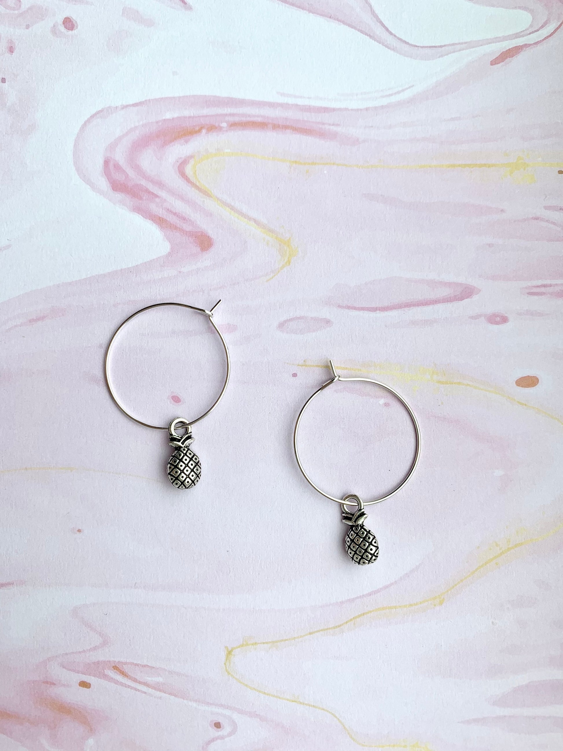 Super cute pineapple earrings. Small silver coloured pineapple charm on silver plated hoos. hoop earrings. popular earrings. cheap earrings. 