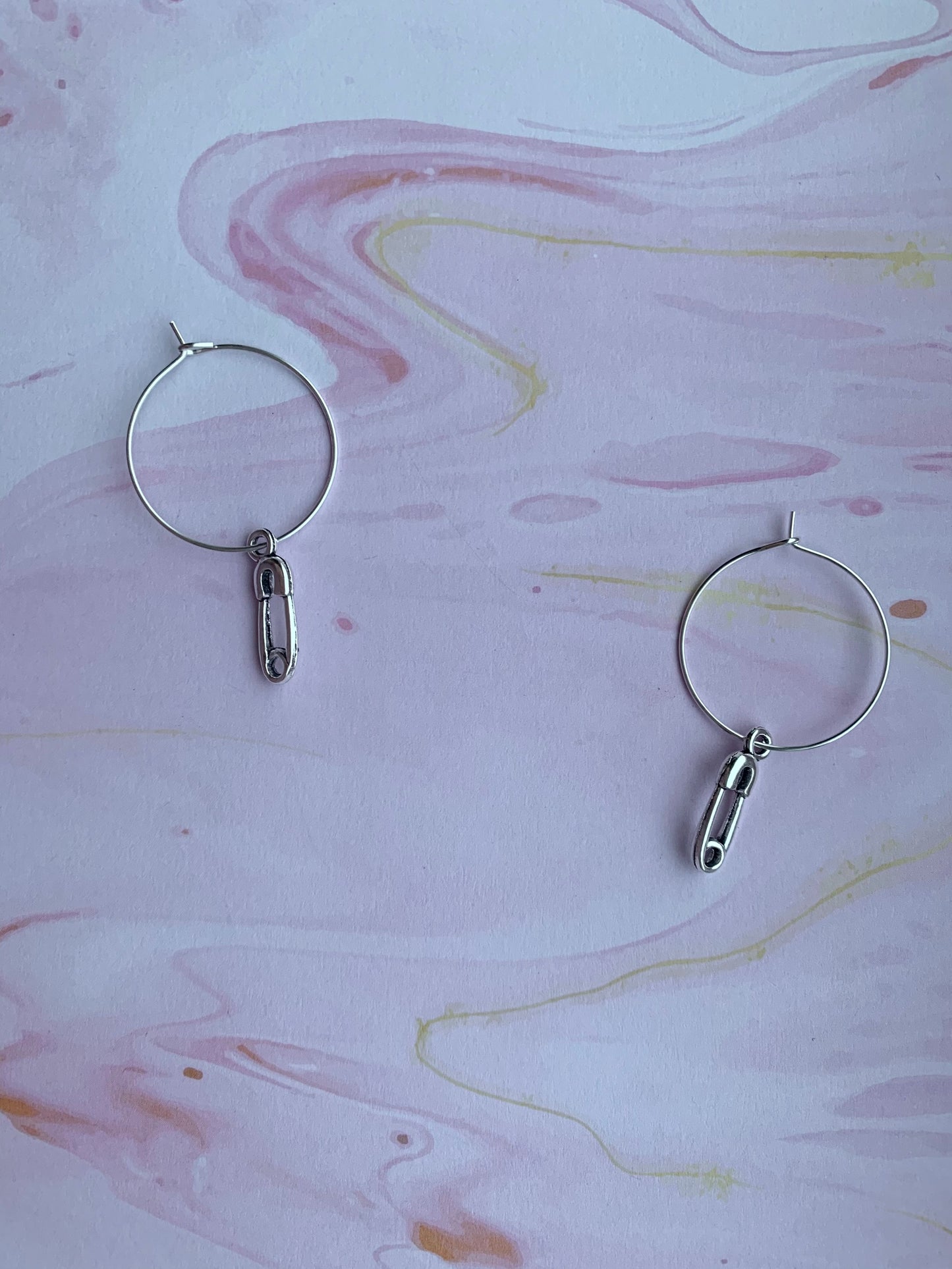 goth earrings. emo earrings. Silver coloured alloy safety pin charm on silver plated hoops. hoop earrings. funky earrings. 