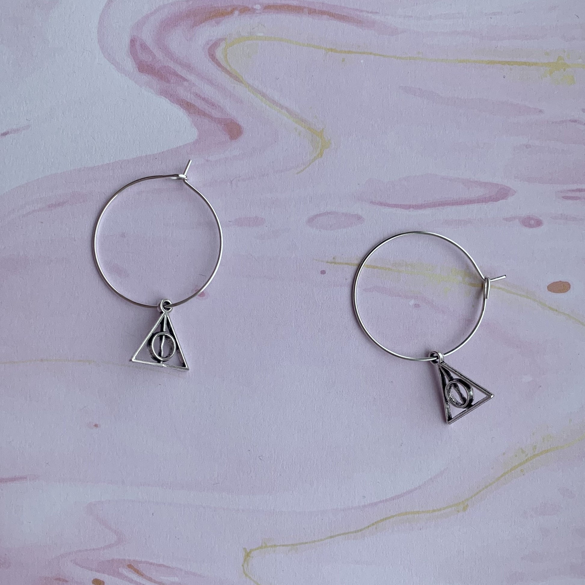Triangle with circle and stick through the middle charms on silver plated hoops. magical earrings. harry potter earrings. cosplay earrings. 