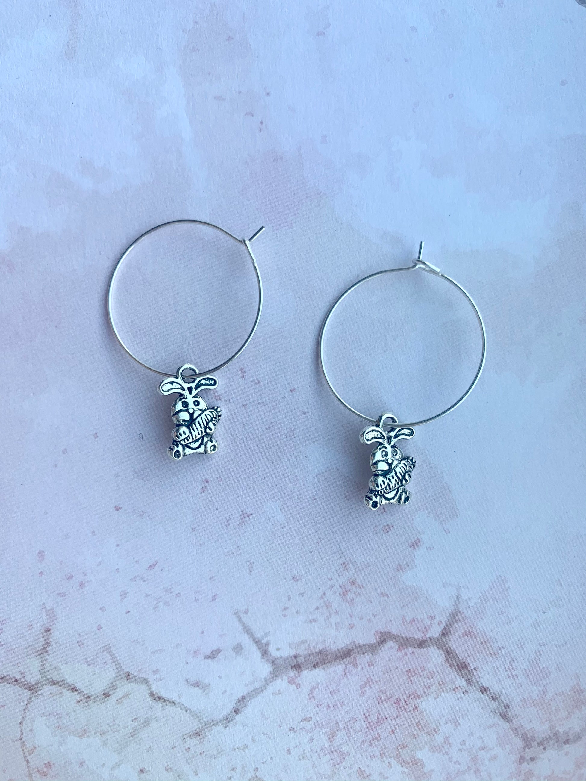 Alloy silver cartoon bunny holding oversized bunny charm on silver plated hoop earrings. easter earrings. Novelty easter earrings. Novelty earrings. Animal earrings.