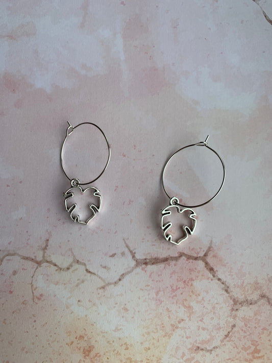 Tropical leaf outline in silver coloured alloy metal charm on silver plated hoops. Hoop earrings. Tropical earrings. Nature earrings. 